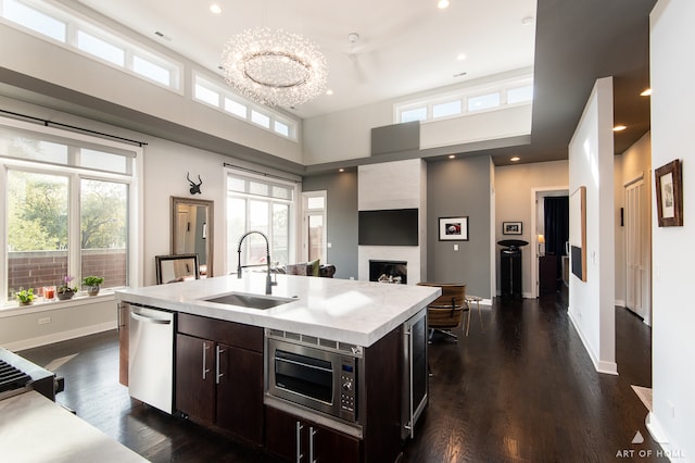 kitchen featuring a high ceiling, a center island with sink, sink, dark brown cabinetry, and stainless steel appliances