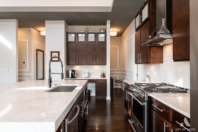 kitchen with dark hardwood / wood-style flooring, dark brown cabinets, stainless steel appliances, a kitchen island with sink, and sink