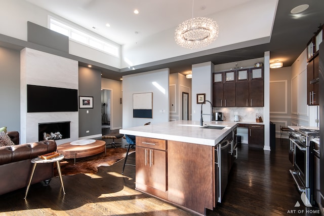 kitchen featuring dark brown cabinetry, sink, stainless steel appliances, a kitchen bar, and a kitchen island with sink