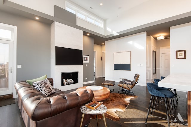 living room featuring dark hardwood / wood-style floors, a premium fireplace, and a towering ceiling