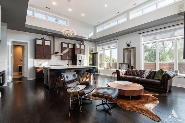 living room with a chandelier, dark hardwood / wood-style flooring, and a towering ceiling