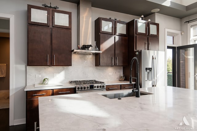 kitchen with sink, wall chimney exhaust hood, decorative backsplash, dark brown cabinets, and stainless steel appliances