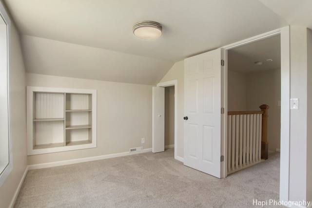 additional living space featuring light colored carpet and vaulted ceiling