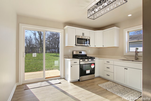 kitchen with a wealth of natural light, white cabinetry, sink, and appliances with stainless steel finishes