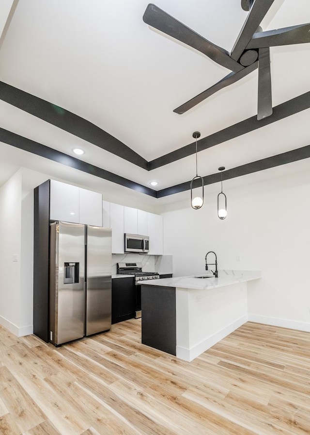 kitchen with white cabinets, decorative light fixtures, light wood-type flooring, and stainless steel appliances