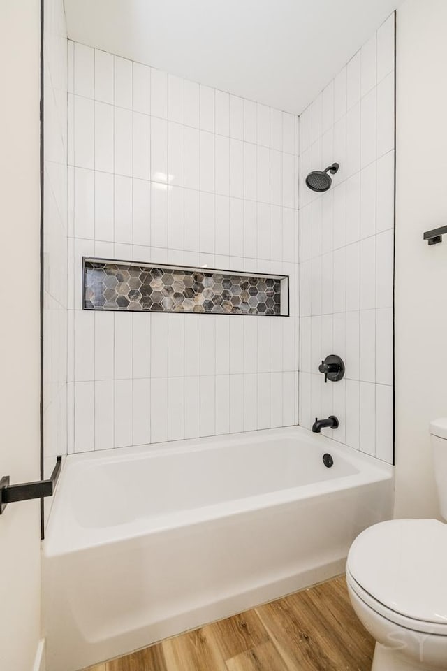 bathroom with hardwood / wood-style floors, tiled shower / bath combo, and toilet