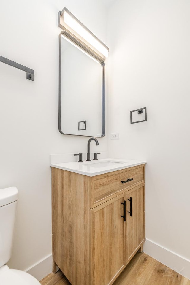 bathroom featuring vanity, wood-type flooring, and toilet