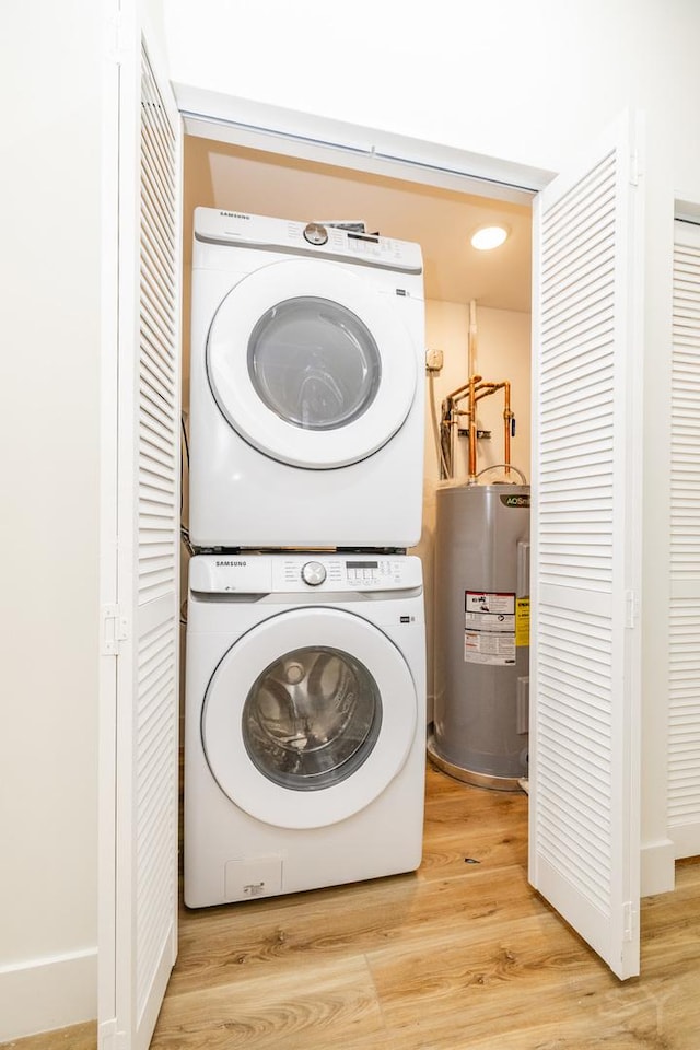 washroom featuring water heater, hardwood / wood-style floors, and stacked washing maching and dryer