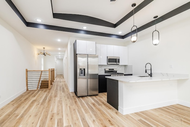 kitchen featuring sink, stainless steel appliances, light hardwood / wood-style floors, decorative light fixtures, and white cabinets