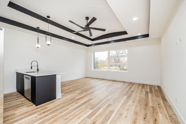 bar with dishwasher, a raised ceiling, sink, hanging light fixtures, and light hardwood / wood-style floors