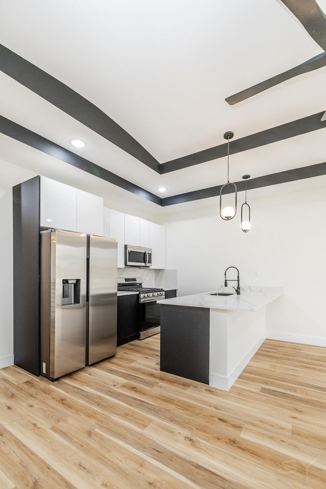 kitchen with white cabinets, light hardwood / wood-style floors, stainless steel appliances, and hanging light fixtures