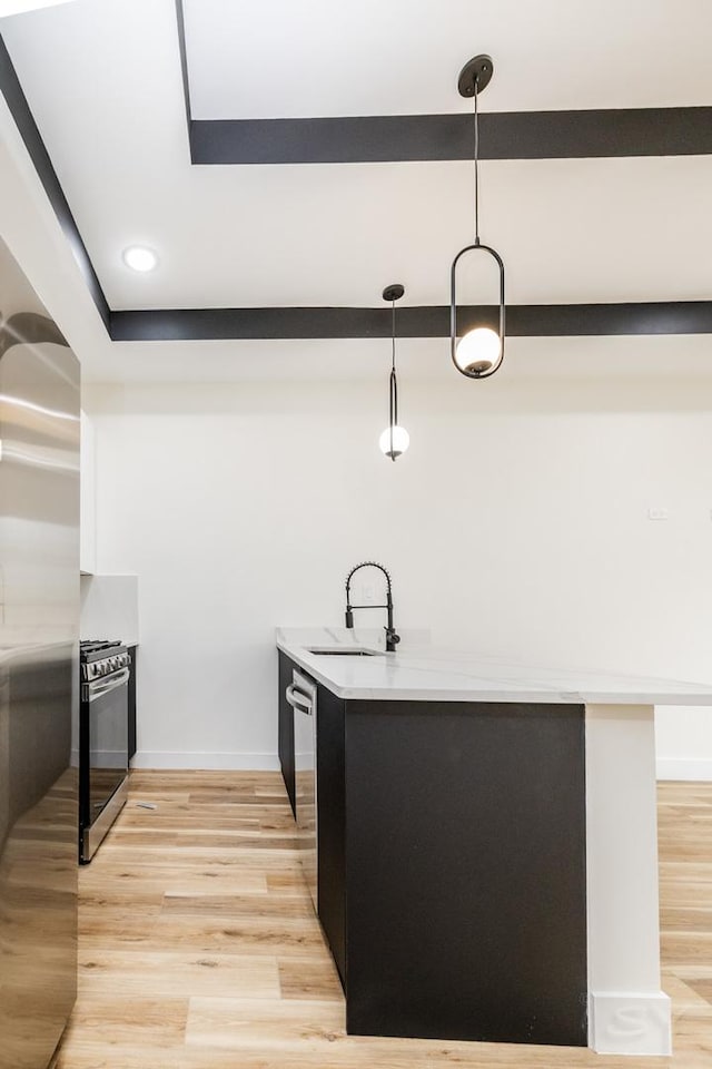 kitchen featuring stainless steel appliances, sink, hanging light fixtures, and light wood-type flooring