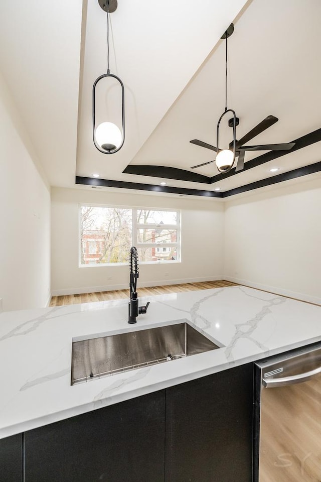 kitchen featuring pendant lighting, sink, light hardwood / wood-style flooring, stainless steel dishwasher, and light stone counters