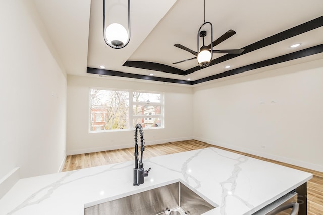 room details featuring light stone countertops, a raised ceiling, and sink