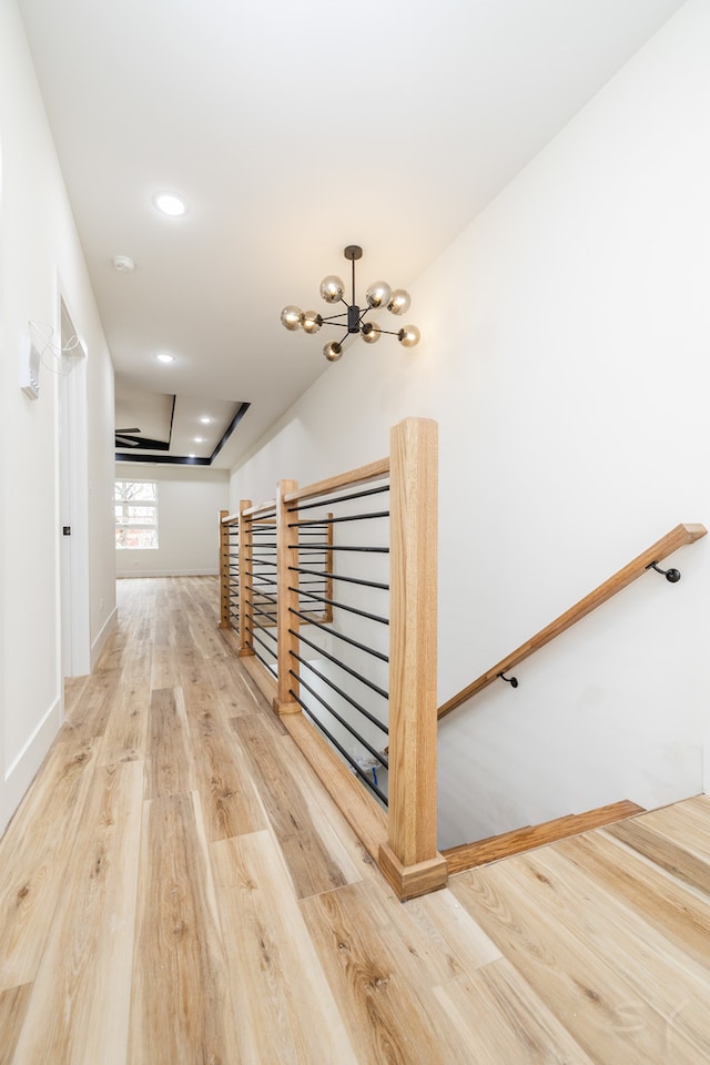 hallway featuring hardwood / wood-style flooring, a tray ceiling, and a notable chandelier