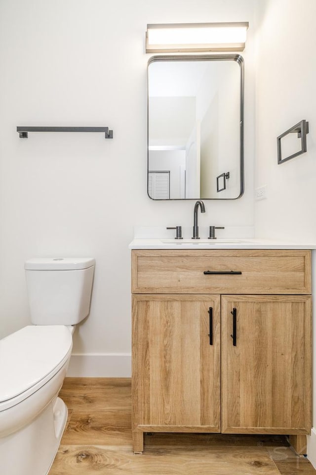 bathroom with hardwood / wood-style floors, vanity, and toilet