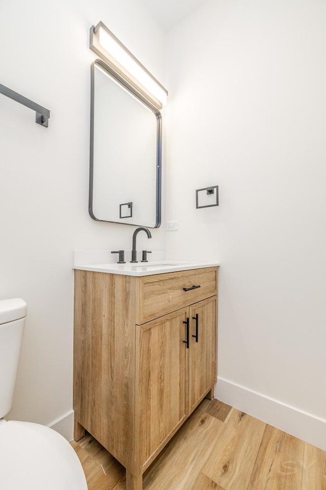 bathroom featuring toilet, vanity, and hardwood / wood-style flooring