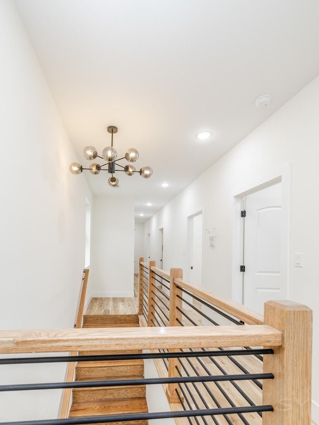 stairs with hardwood / wood-style flooring and a chandelier