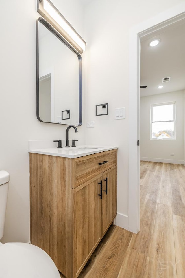 bathroom with hardwood / wood-style floors, vanity, and toilet