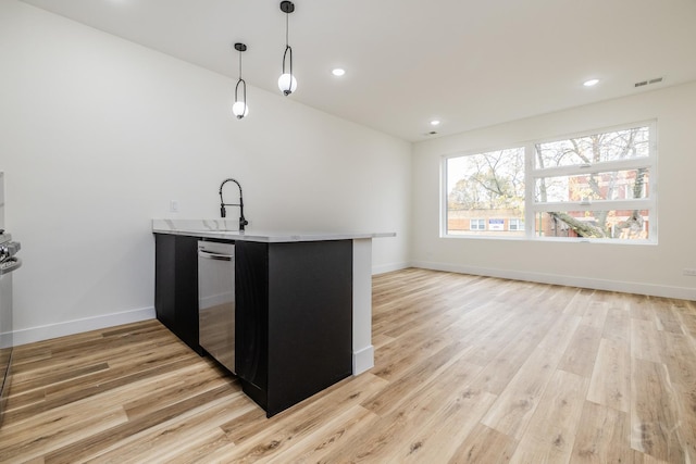 kitchen featuring kitchen peninsula, sink, decorative light fixtures, and light wood-type flooring