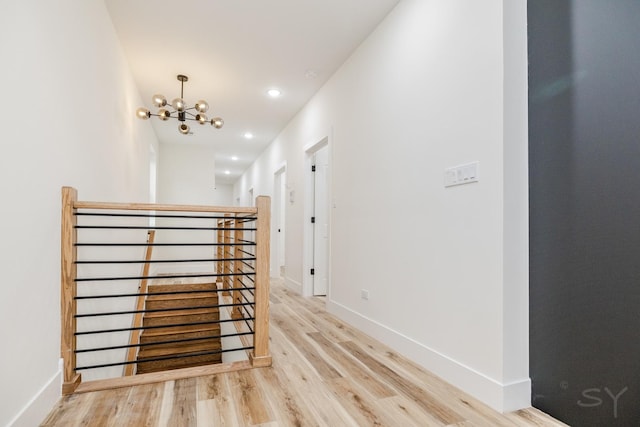 hallway with an inviting chandelier and light hardwood / wood-style flooring