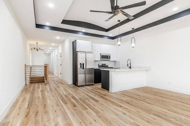 kitchen with white cabinets, a raised ceiling, stainless steel appliances, and hanging light fixtures