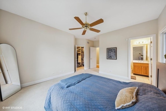 bedroom featuring ceiling fan, a spacious closet, light carpet, and connected bathroom