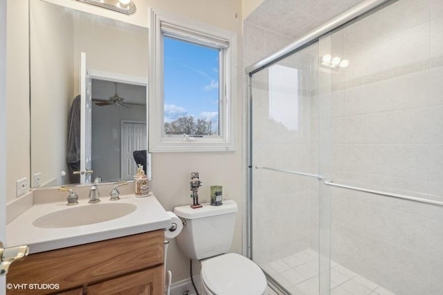 bathroom with ceiling fan, vanity, a shower with shower door, and toilet