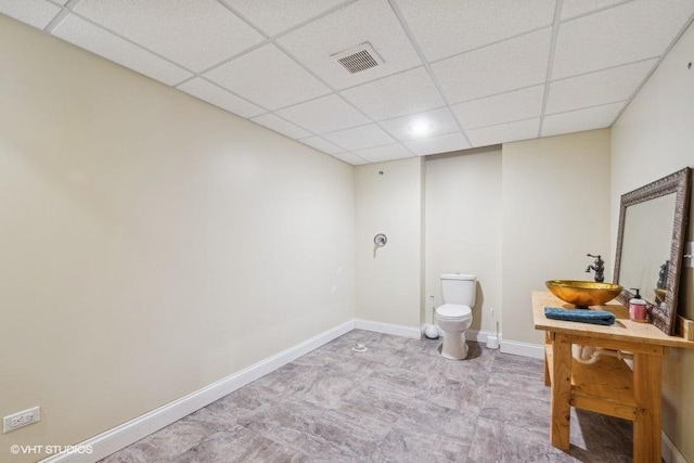 bathroom with a drop ceiling, toilet, and vanity