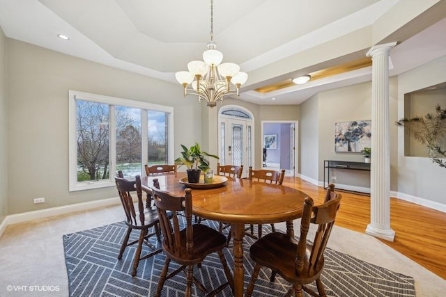 dining space with a chandelier, light hardwood / wood-style floors, ornate columns, and a tray ceiling