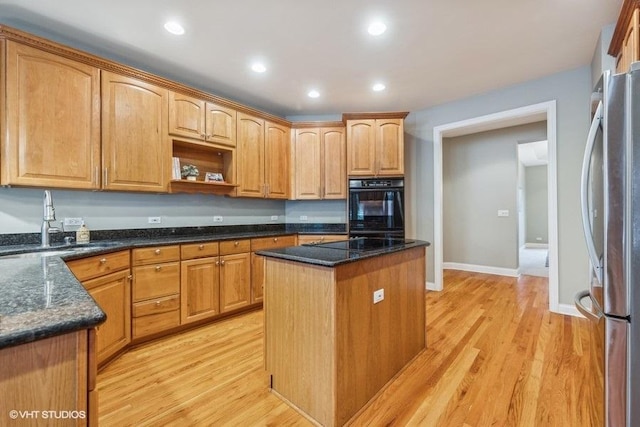 kitchen featuring light hardwood / wood-style floors, a kitchen island, dark stone counters, and black appliances