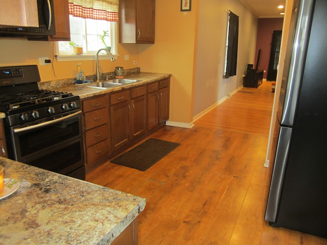 kitchen with appliances with stainless steel finishes, light hardwood / wood-style floors, and sink