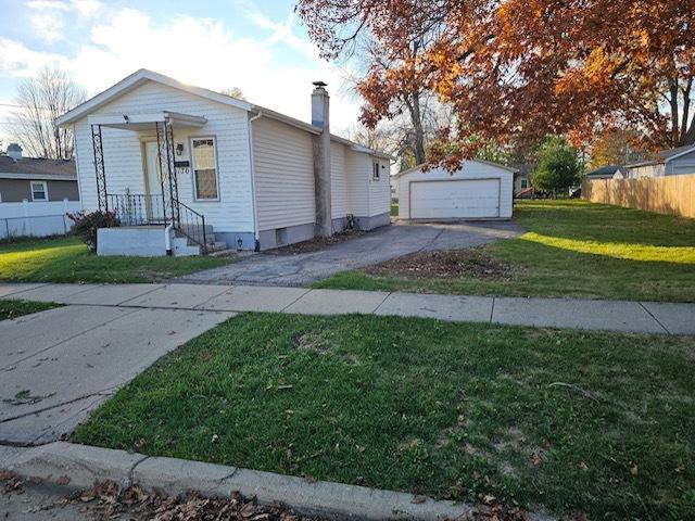 bungalow-style home with a garage, a front lawn, and an outdoor structure