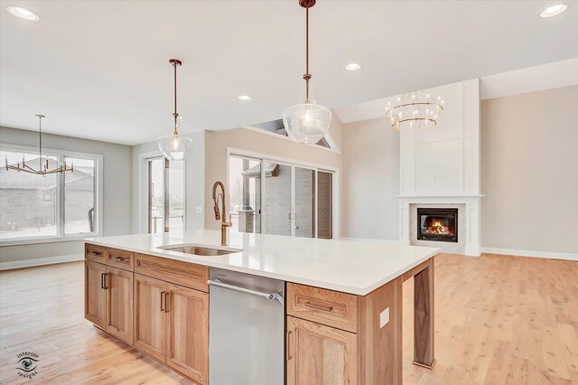 kitchen featuring light wood-type flooring, a center island with sink, an inviting chandelier, and sink