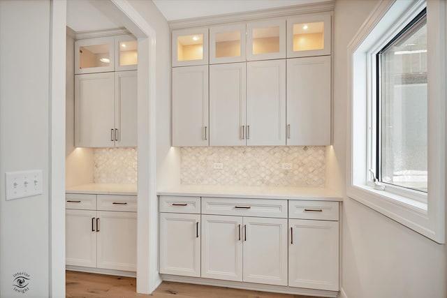 kitchen featuring decorative backsplash, light hardwood / wood-style floors, and white cabinetry