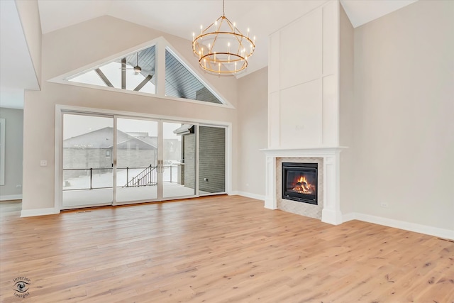 unfurnished living room featuring high vaulted ceiling, a notable chandelier, and light wood-type flooring