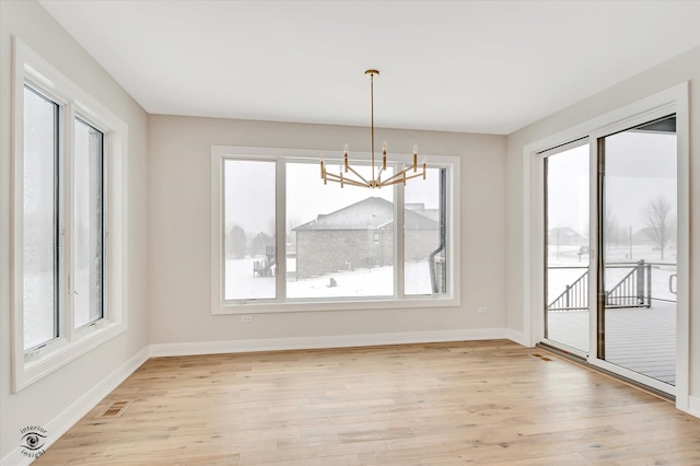 unfurnished dining area featuring a chandelier and light hardwood / wood-style floors