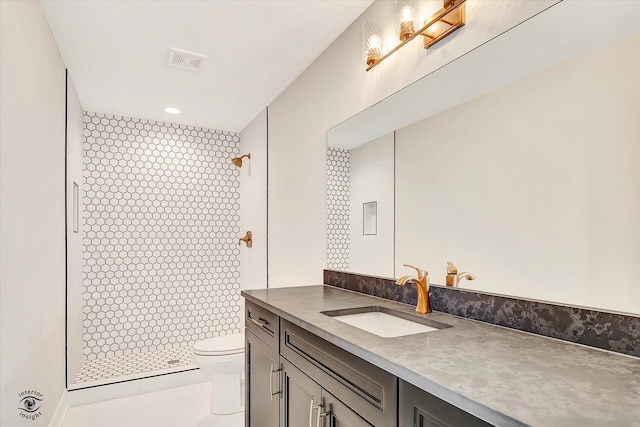 bathroom featuring vanity, toilet, and tiled shower