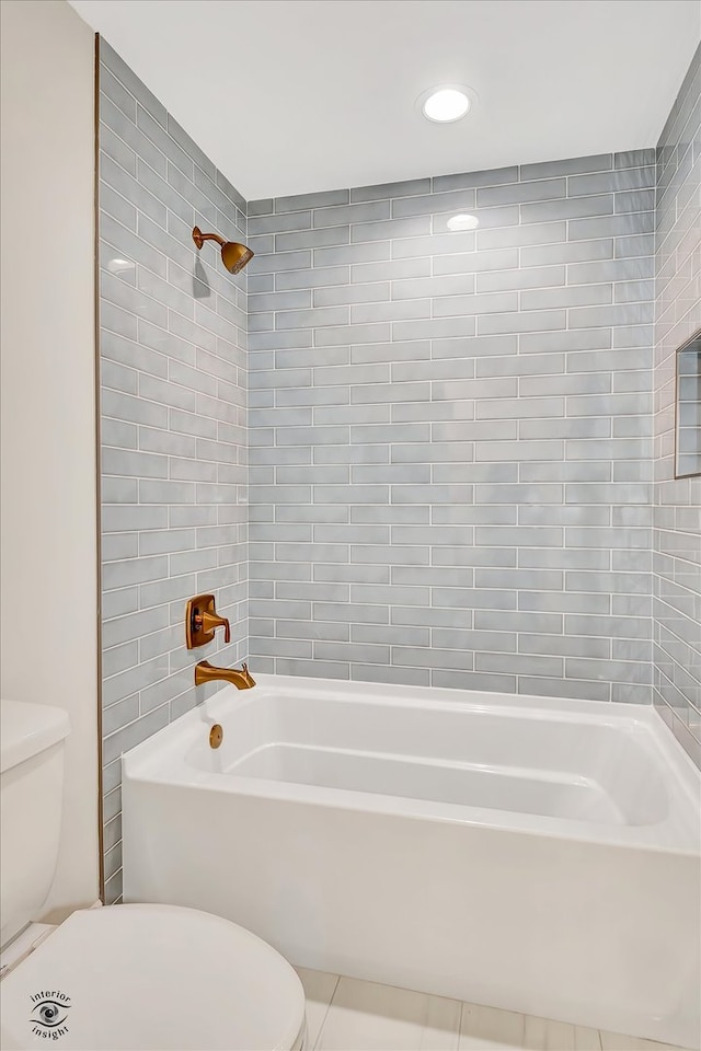 bathroom with tile patterned floors, toilet, and tiled shower / bath