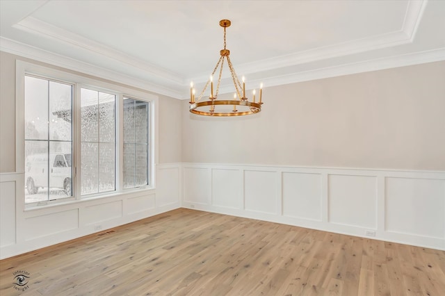 unfurnished room with a raised ceiling, light hardwood / wood-style floors, and an inviting chandelier