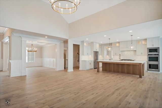 kitchen with white cabinetry, a large island, a notable chandelier, light wood-type flooring, and appliances with stainless steel finishes