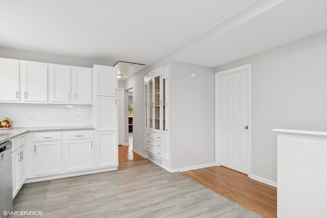 kitchen with dishwasher, white cabinets, light hardwood / wood-style flooring, tasteful backsplash, and light stone counters