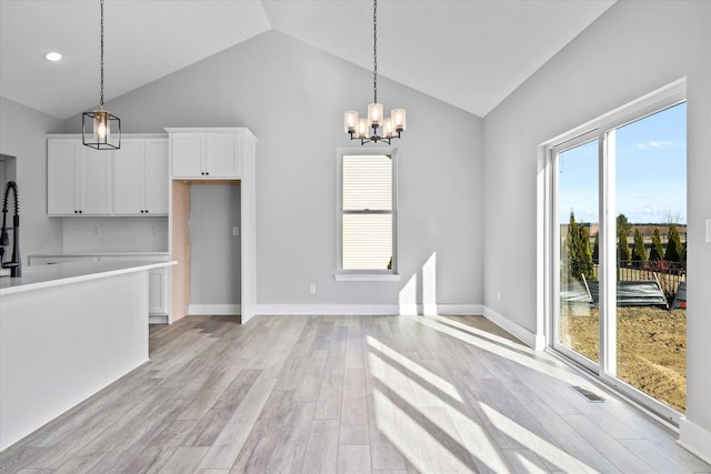 kitchen with white cabinetry, plenty of natural light, vaulted ceiling, and light wood-type flooring