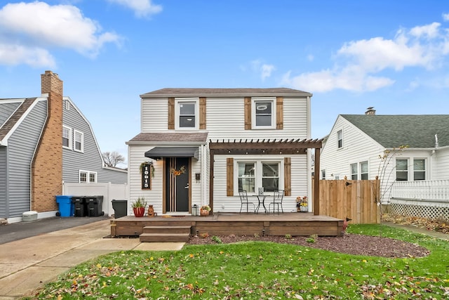 front of property with a pergola, a front yard, and a deck