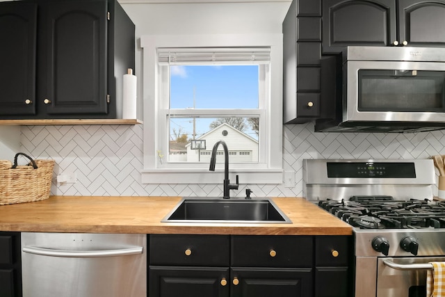 kitchen with decorative backsplash, appliances with stainless steel finishes, butcher block countertops, and sink