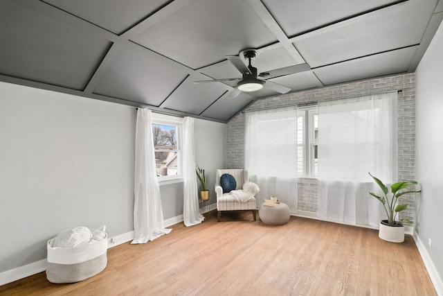 sitting room with ceiling fan, light hardwood / wood-style flooring, brick wall, and coffered ceiling