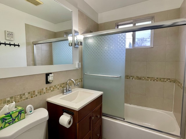 full bathroom with decorative backsplash, vanity, toilet, and bath / shower combo with glass door