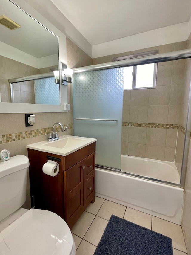 full bathroom with vanity, shower / bath combination with glass door, tile patterned floors, toilet, and tile walls