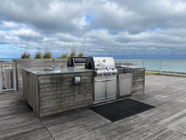 wooden deck with grilling area, sink, a water view, and exterior kitchen