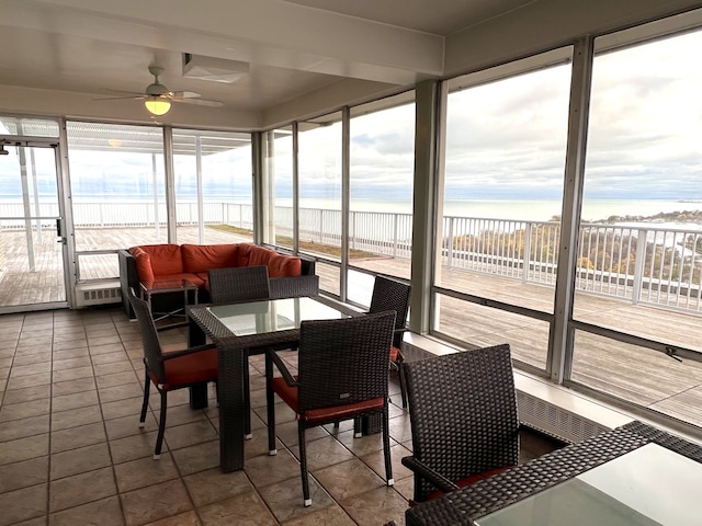 sunroom / solarium featuring ceiling fan, a water view, and a healthy amount of sunlight